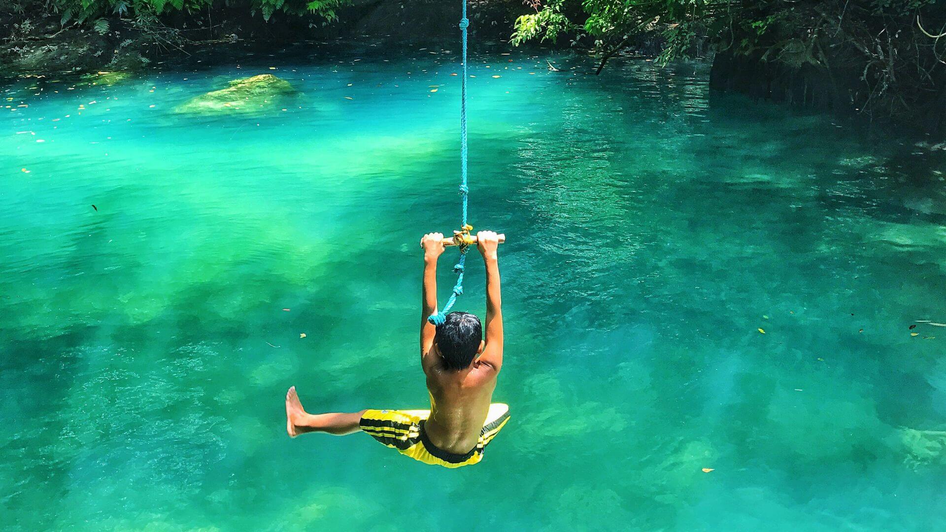 Junge schwingt an Seil in eine Lagune in Cebu Philippinen